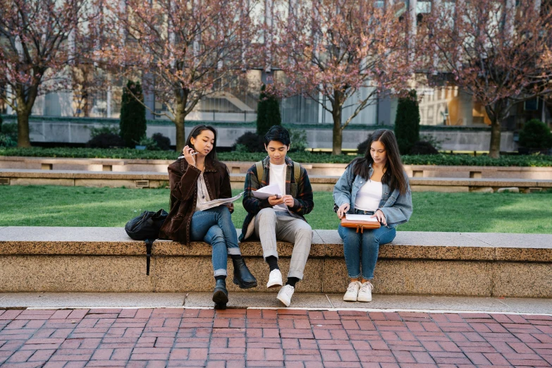 three people sitting on a bench with some buildings behind them