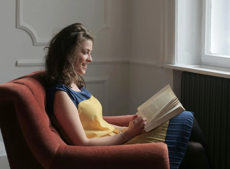 a girl sitting in a chair with an open book