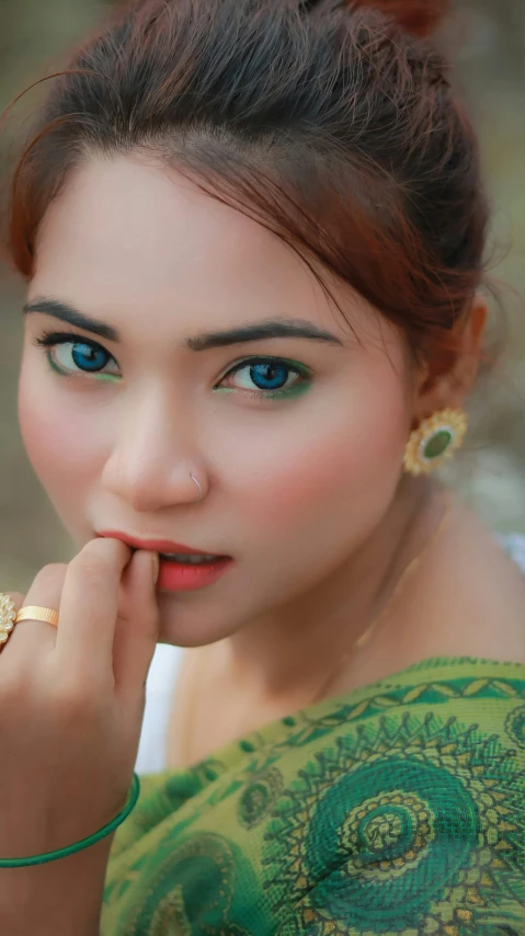 young woman with blue eyes in green dress holding ring