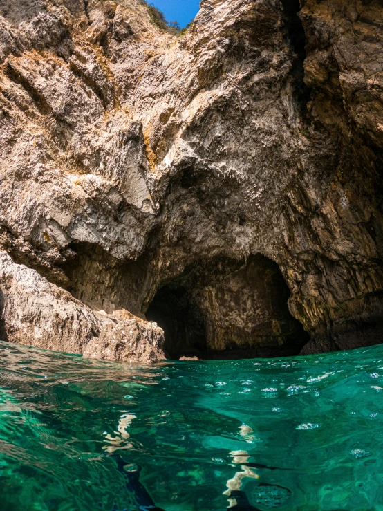 an image of two people swimming in the sea near a cliff