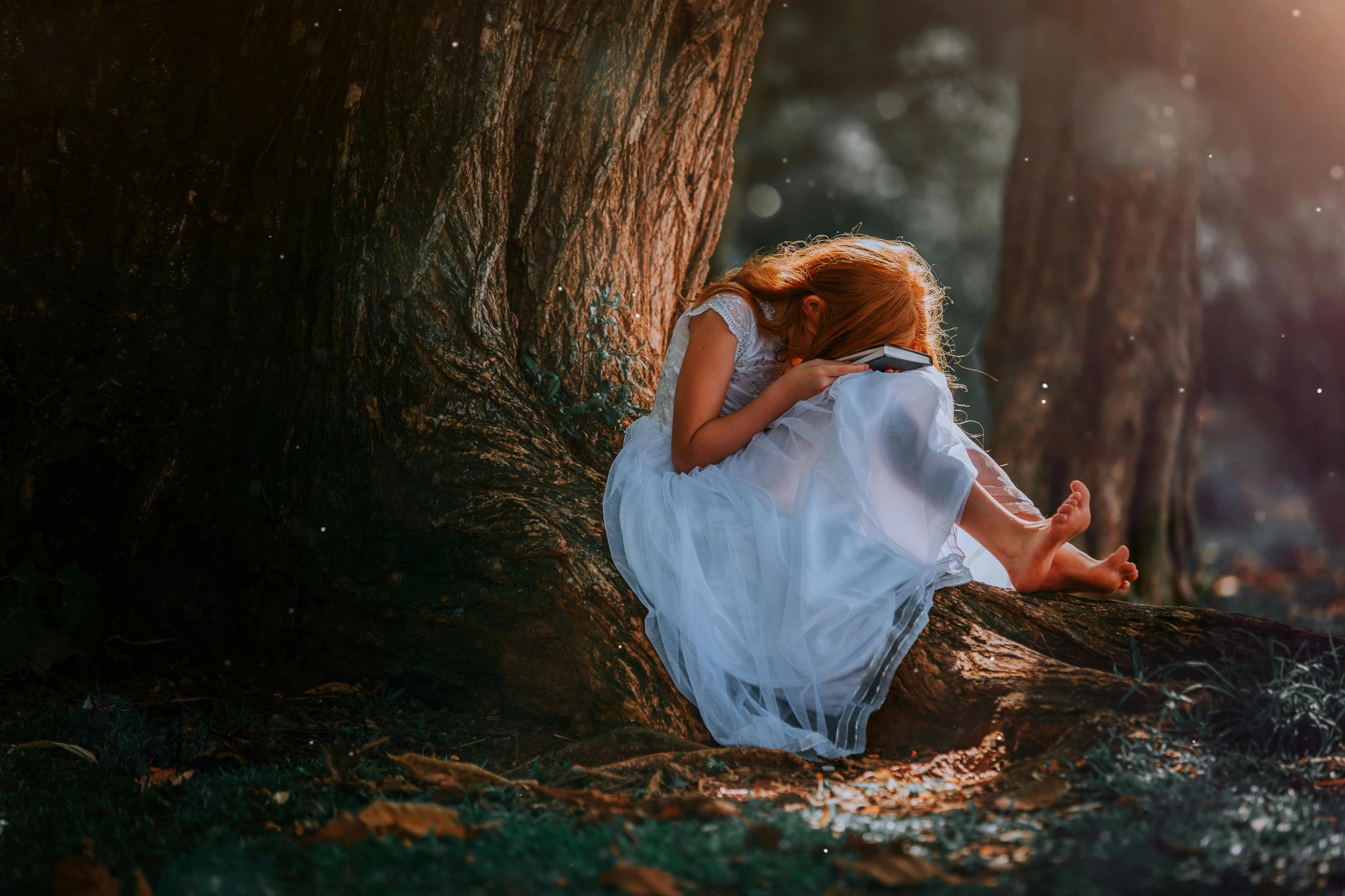 girl in white sitting in the middle of a forest