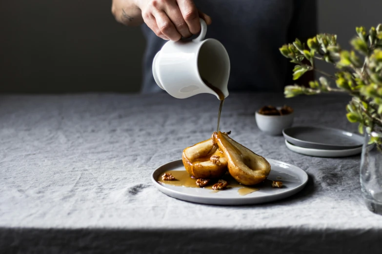 a person pouring syrup on a plate of food