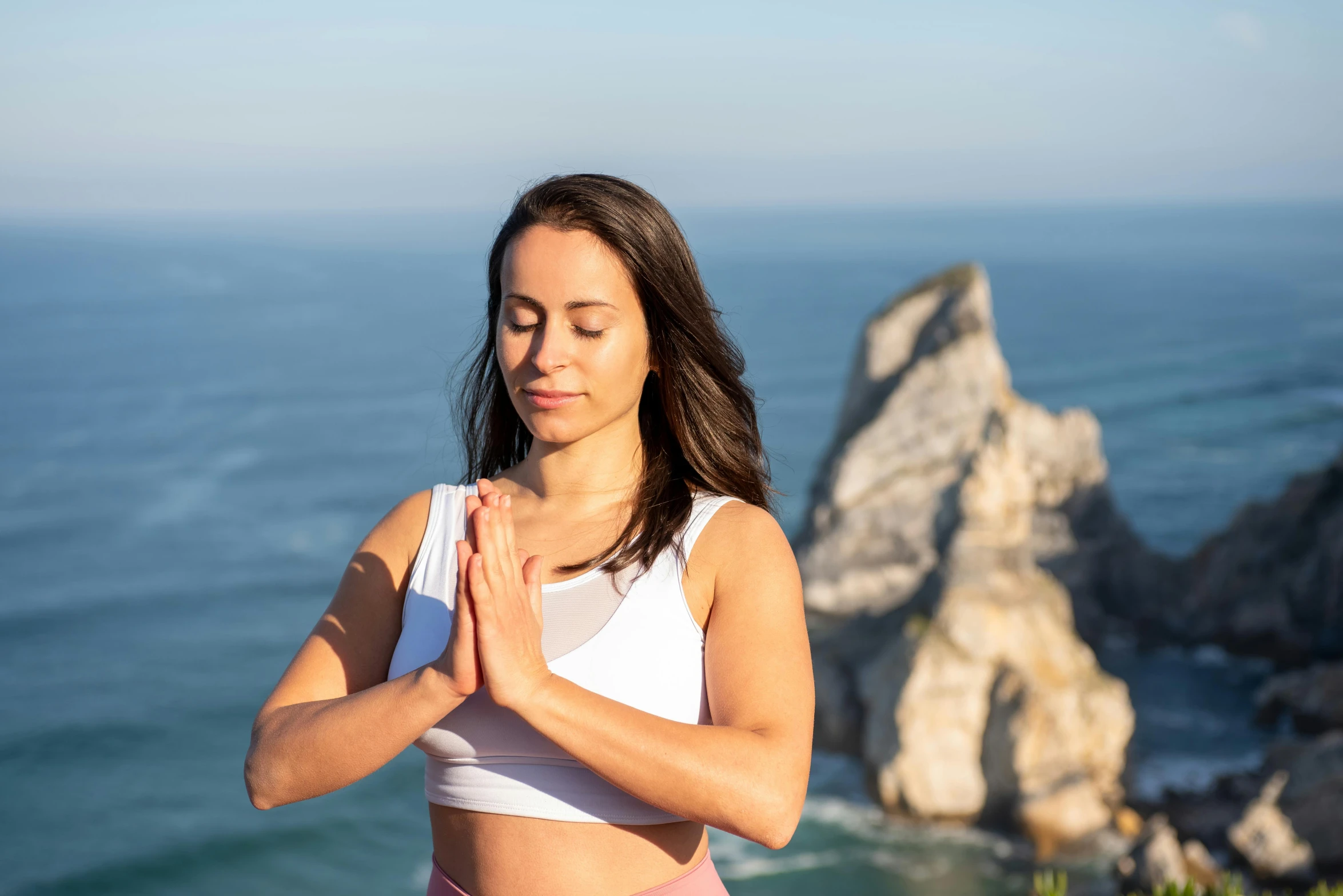 the woman is meditating her energy, with an ocean view in the background