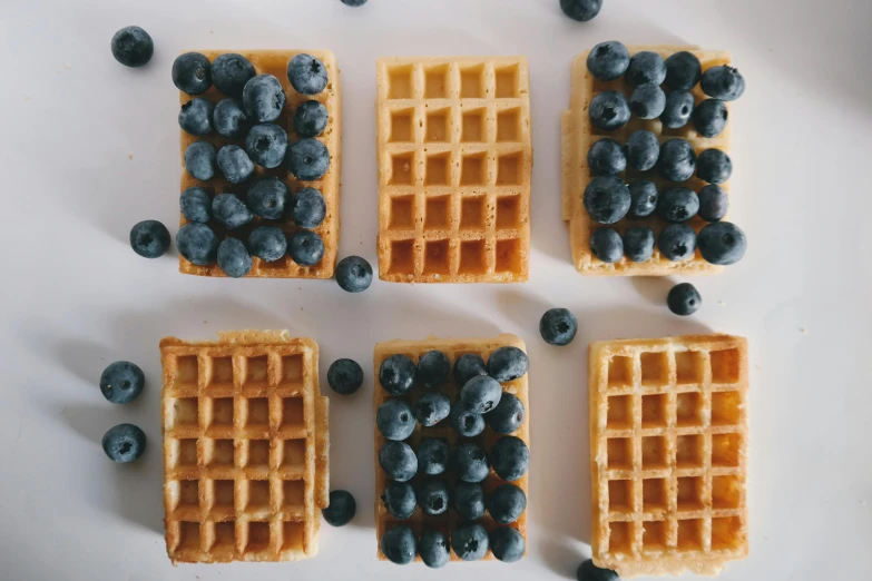 four waffles have blueberries on them and one is broken