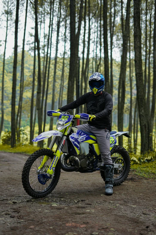 person riding a yellow and white dirt bike on a dirt path