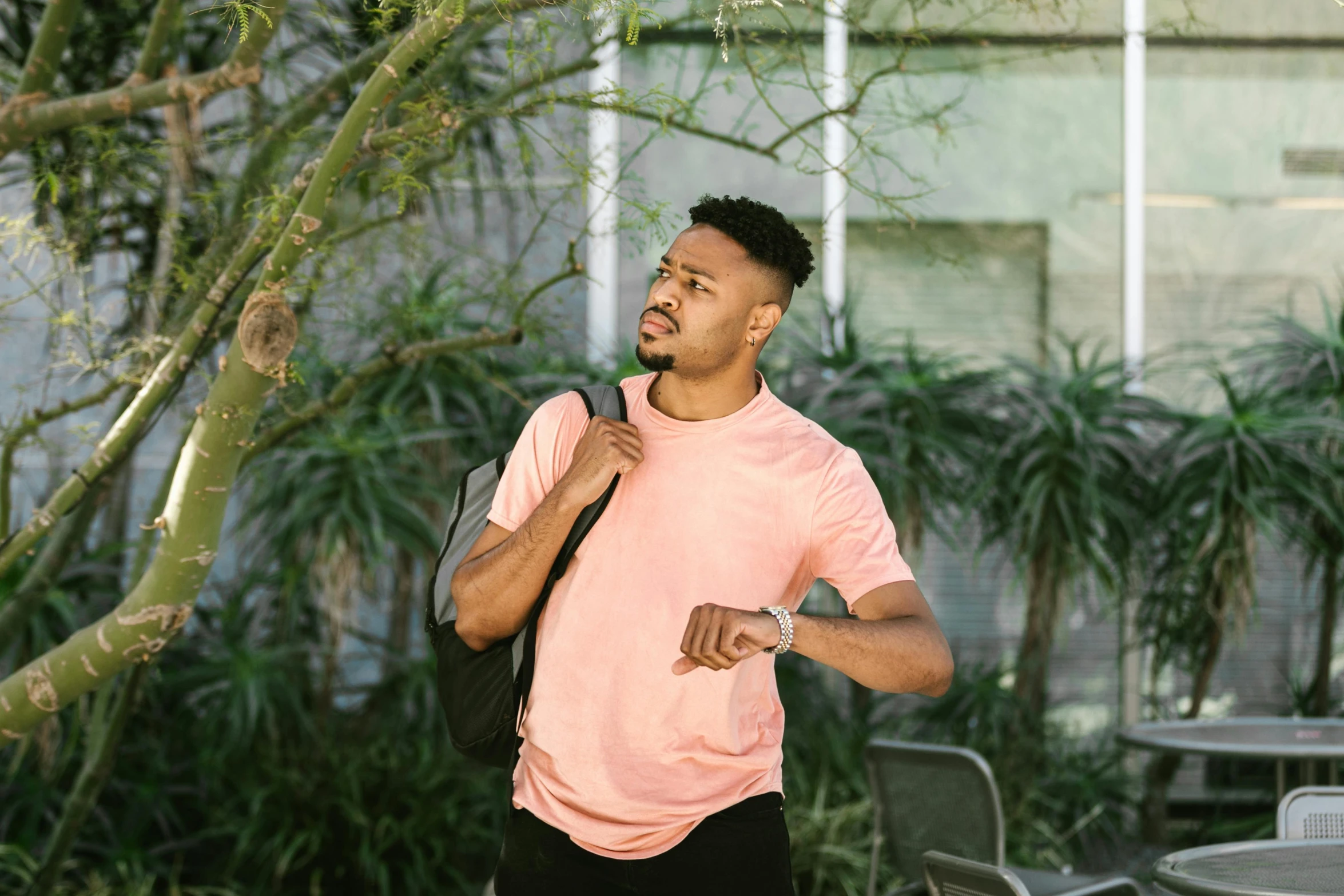 a man holding his back and wearing a pink t - shirt