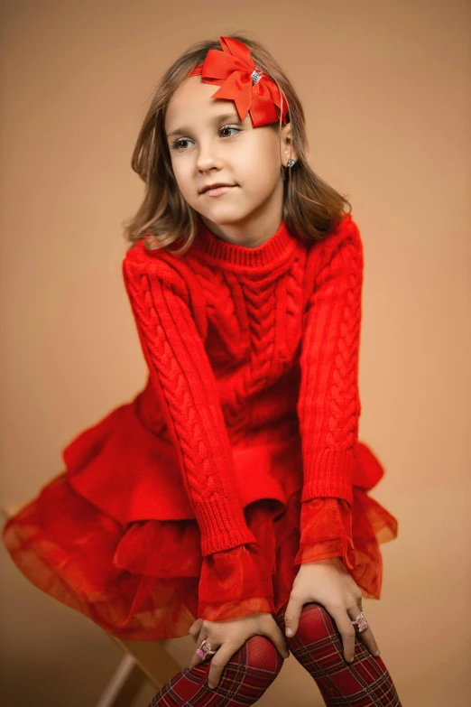 an adorable little girl in red with a knitted hat, dress and socks