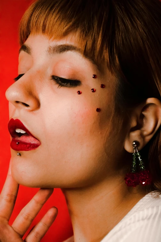 the woman is wearing a pair of earrings with the red flowers on her face