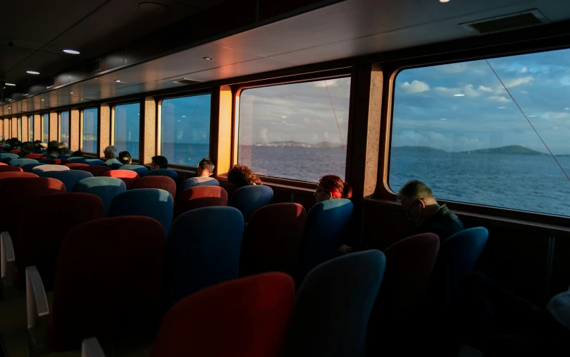 the passenger train has multiple seats and there are people sitting in the car