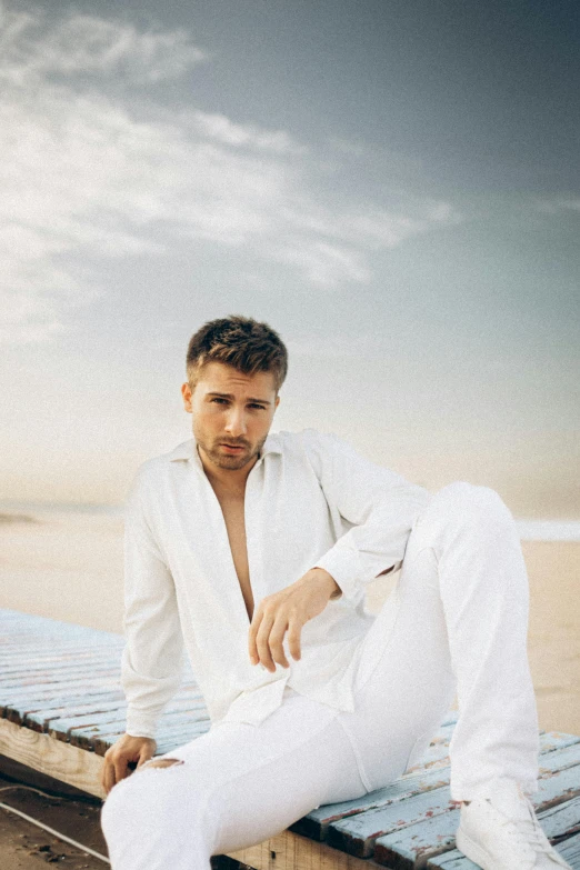 a man leaning on the edge of a building wearing white