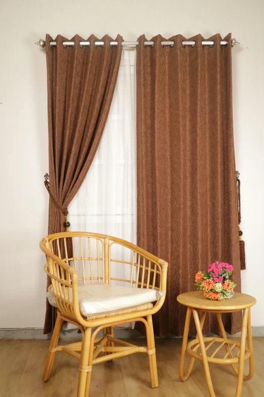 a pair of wooden chairs and a small table next to a window with curtains