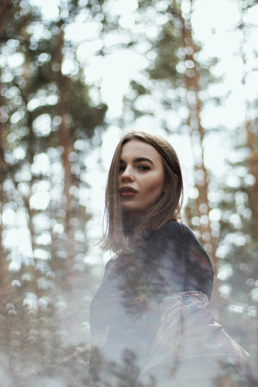 a beautiful woman is standing in the woods looking at soing