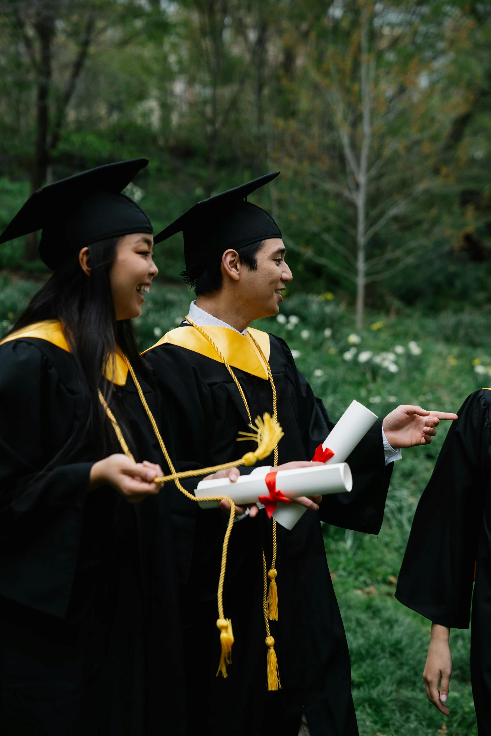 two graduates hold a diploma for a friend