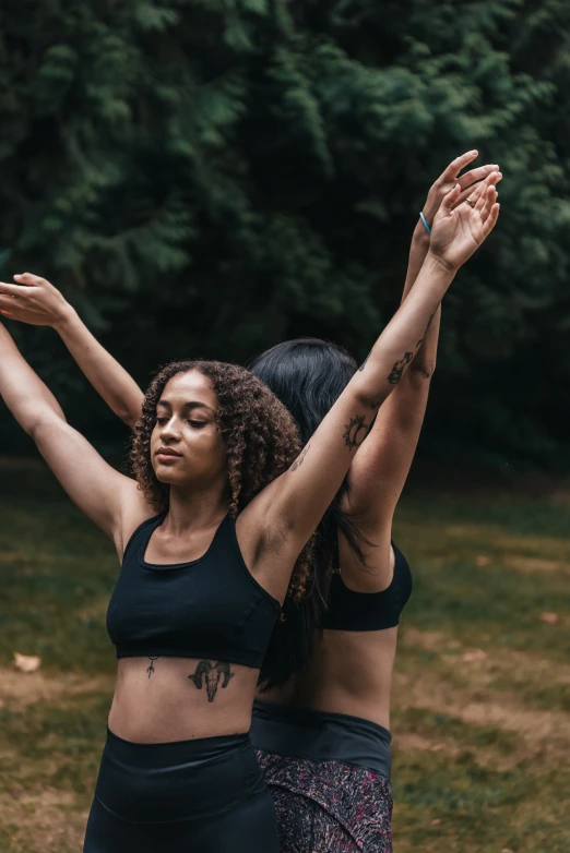 two women in the middle of yoga practice with their arms raised