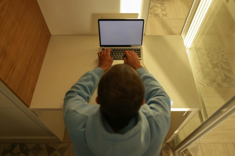 a man in a blue sweater working on a laptop