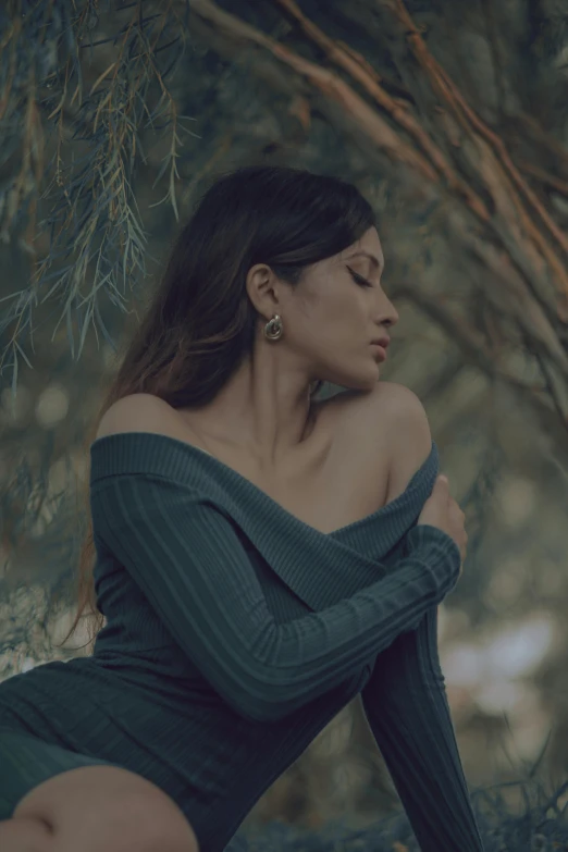 a woman is sitting in the woods and has her back to her chest