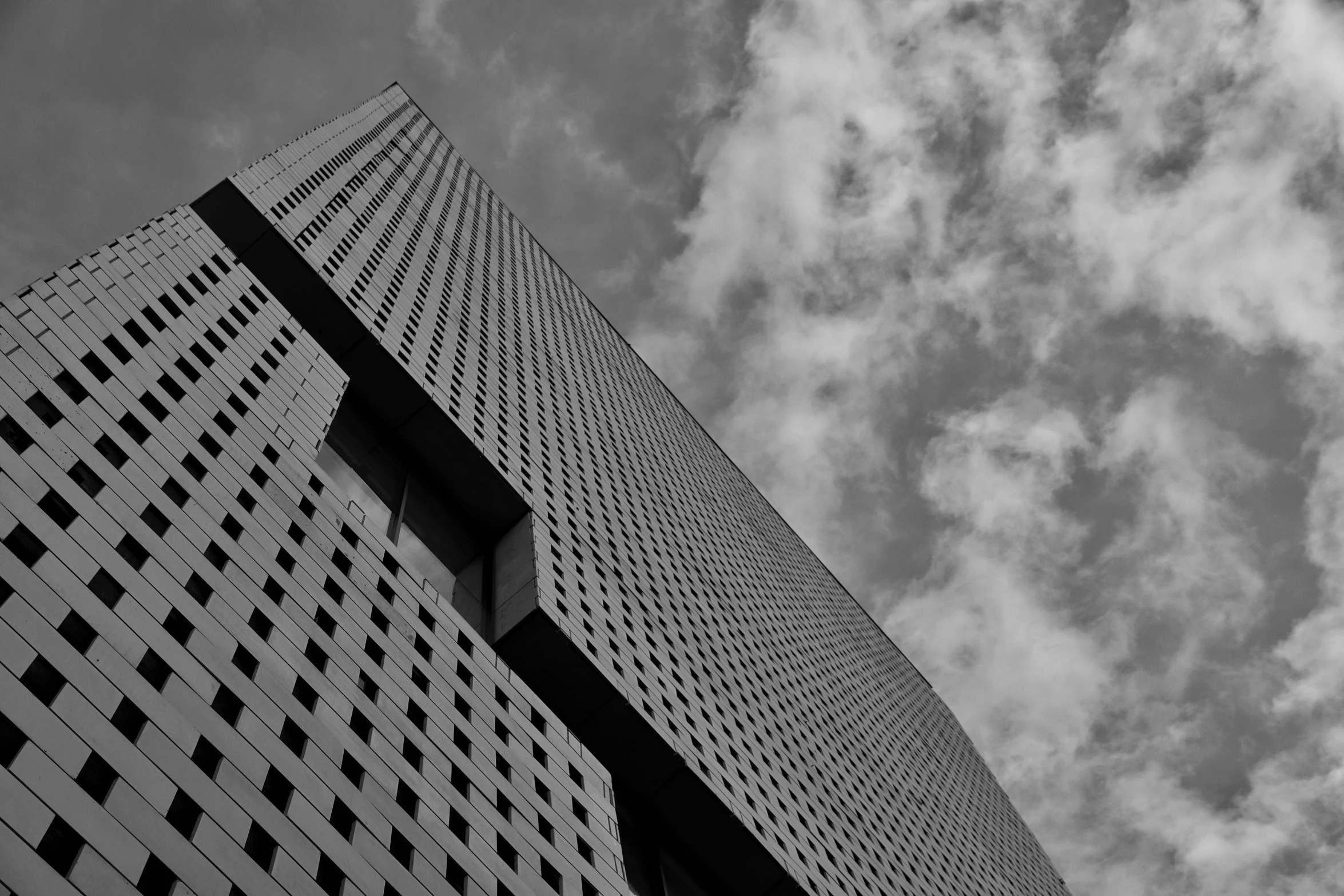 a tall skyscr standing under clouds on a clear day