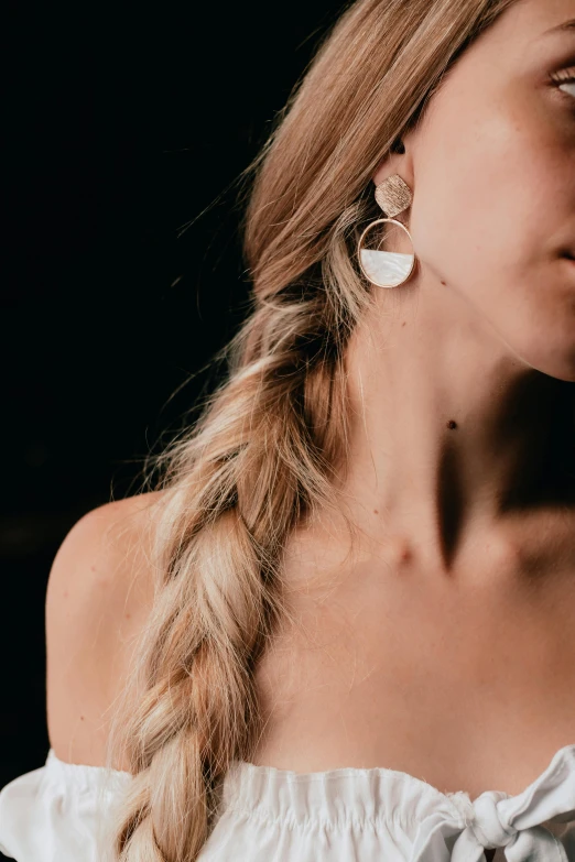 a woman with long hair in a dress and statement earrings