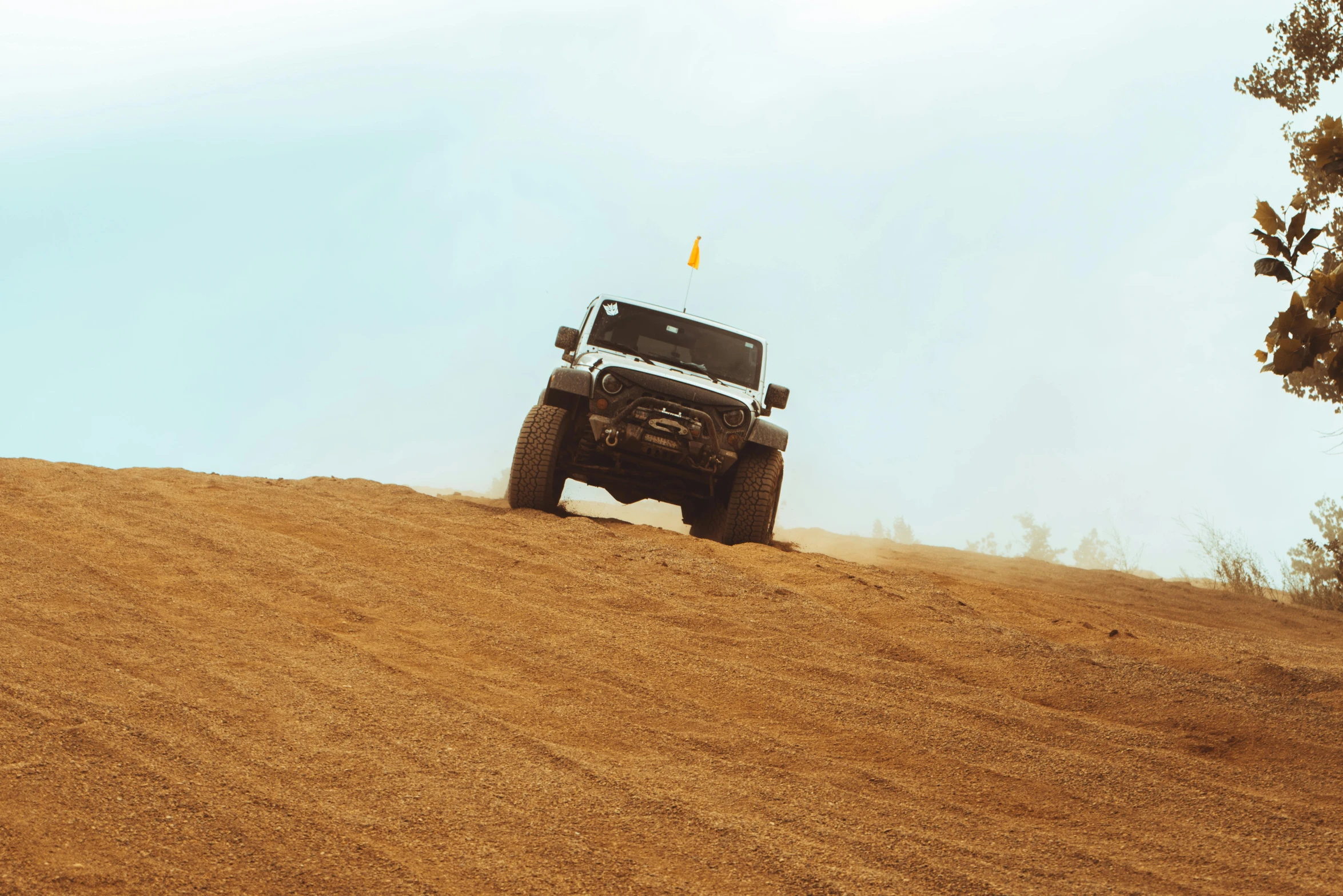 a jeep driving in the desert with dust covering the ground