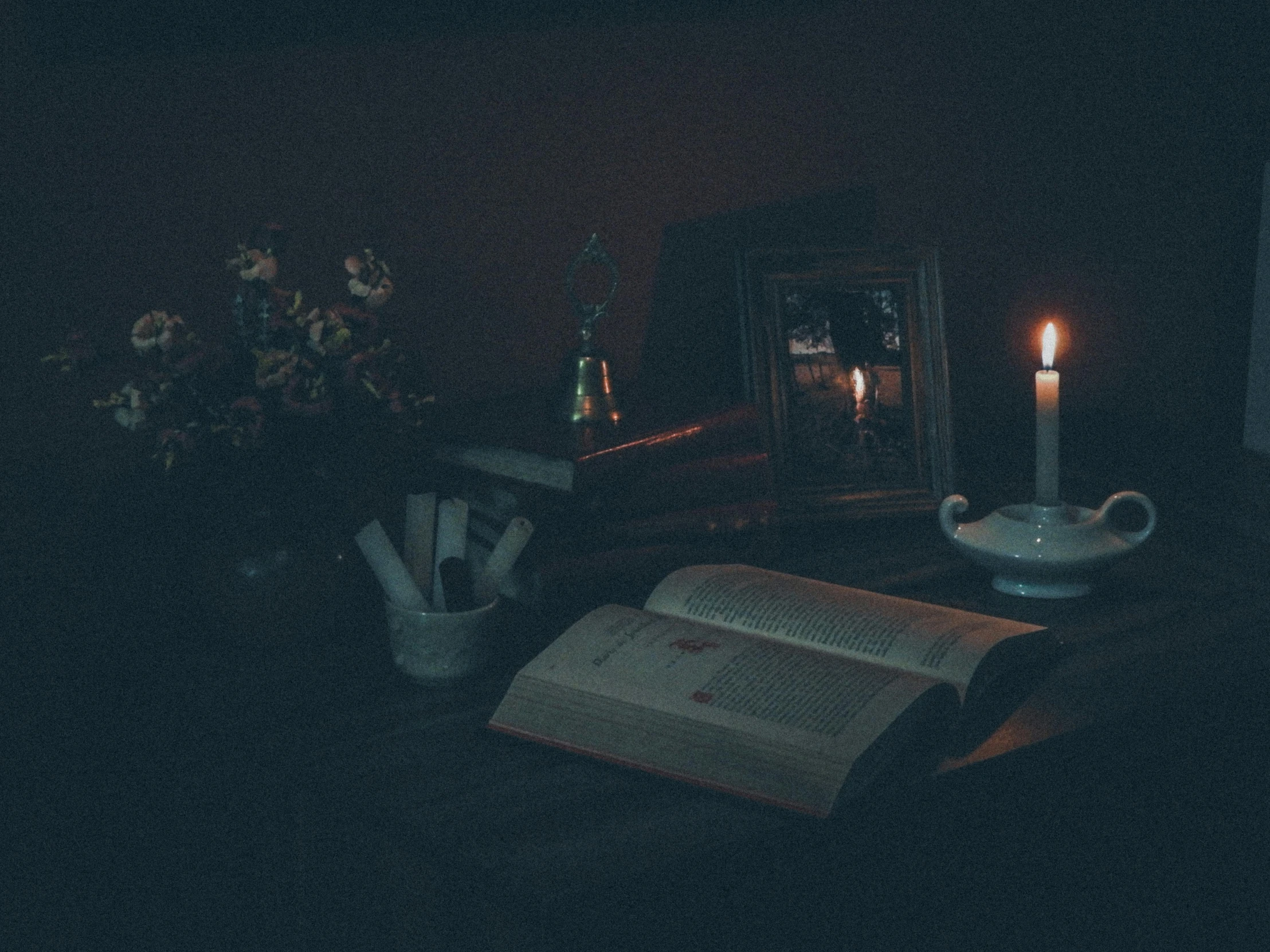 a po of a candle, books and papers on a table