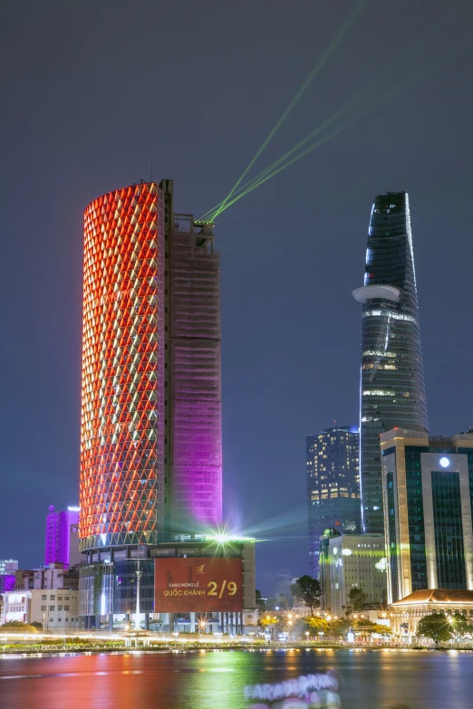 a tall building with multiple lights on it is reflected in water