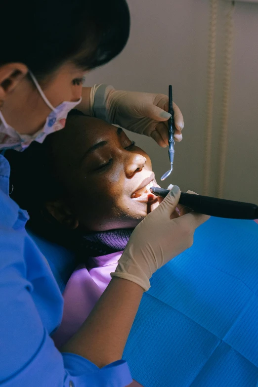 a woman getting her teeth checked with an electric device