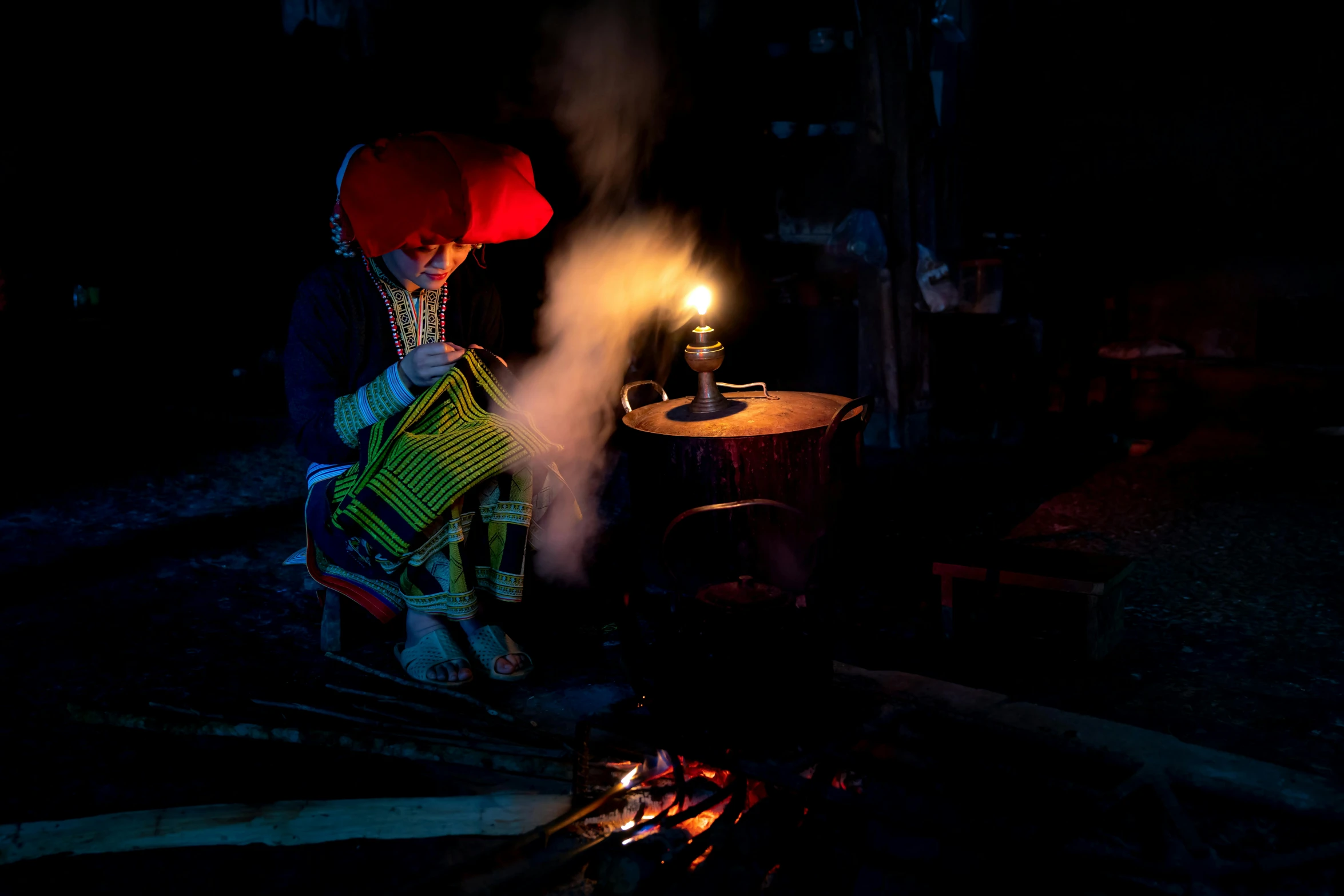 a person holding a lit up candle standing next to a fire