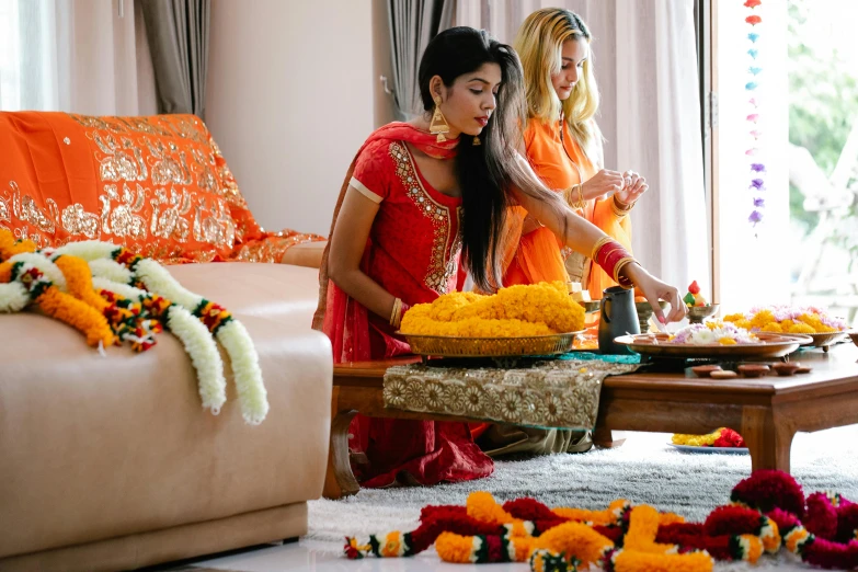 two women making garlands in front of a couch