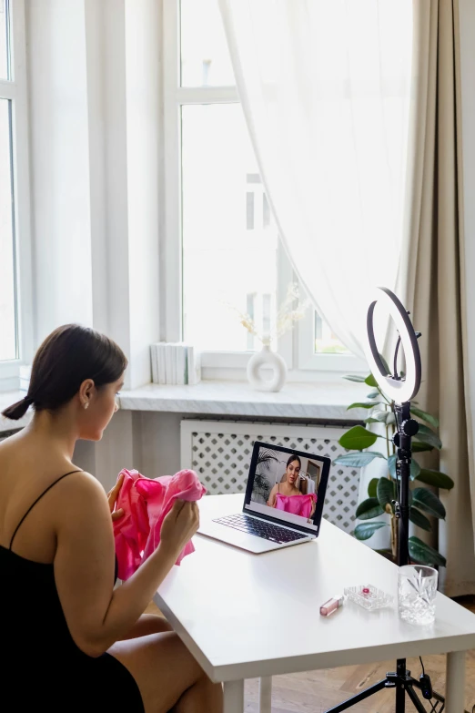 the woman is sitting in her room at the table with her laptop