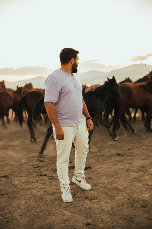 a man standing in front of a herd of horses