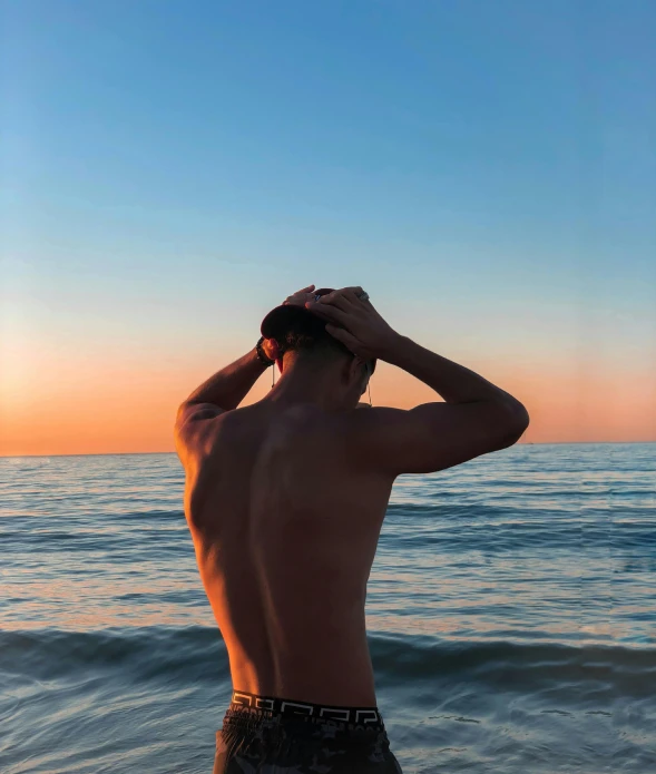 a man standing in the water saluting at the beach