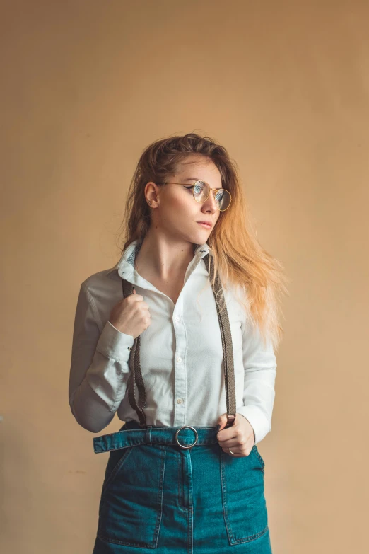 a woman wearing glasses and a white shirt, in front of a brown wall