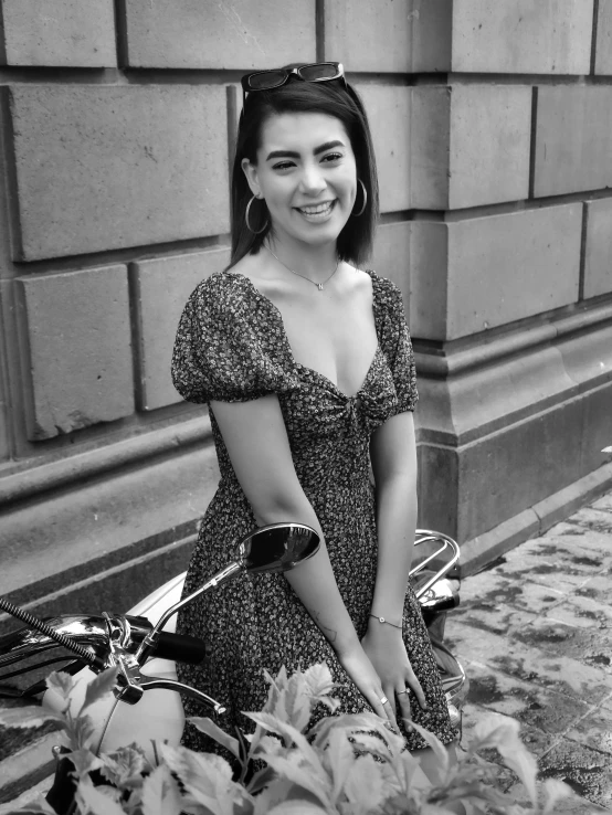 a woman in a dress standing next to a bike