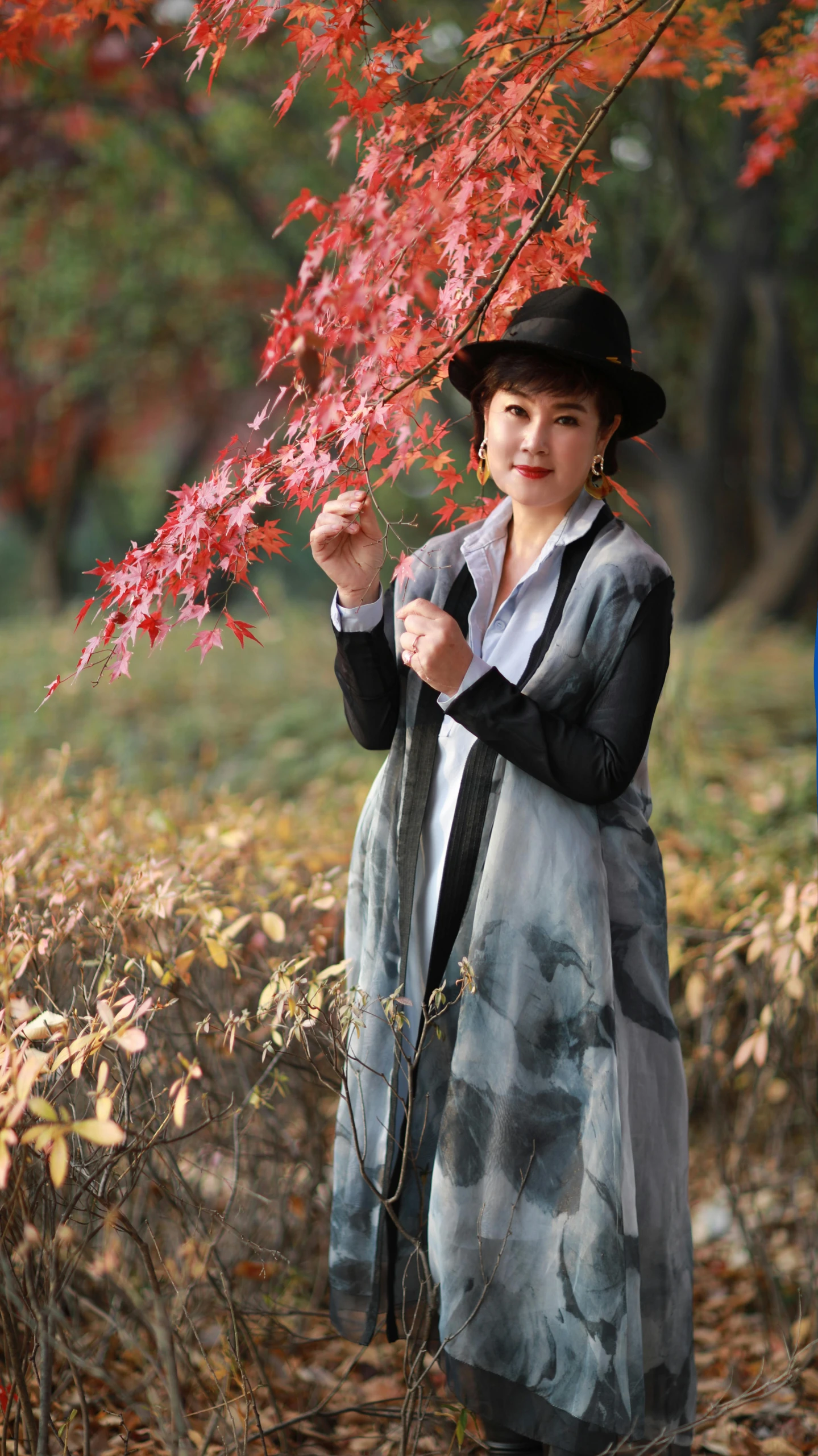 a woman in a black hat is holding leaves