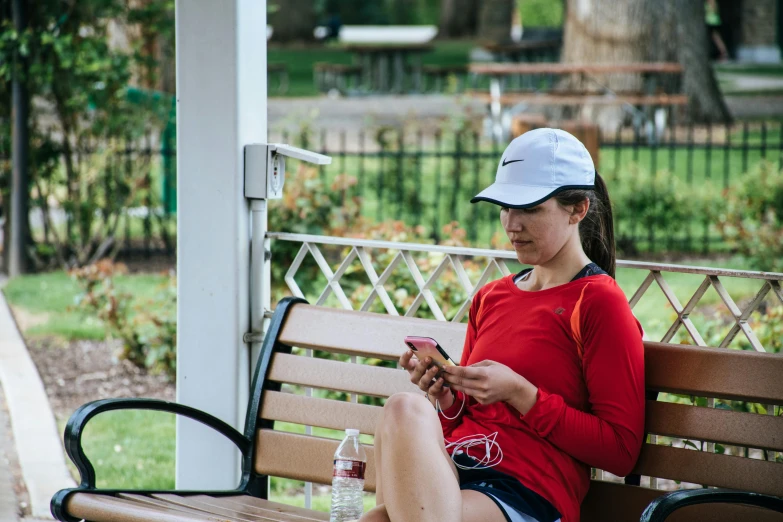 a young woman sitting on a bench, looking at her phone