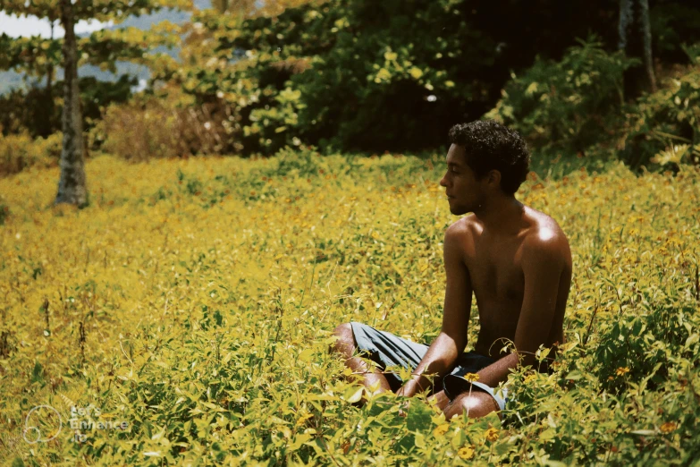 a man sitting on the grass outside doing yoga