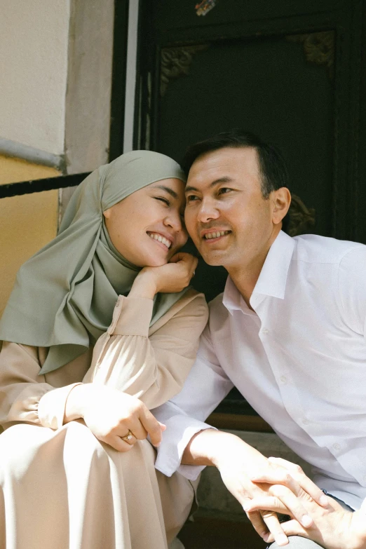 an asian couple sits together in front of the window of a house