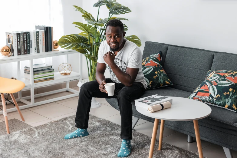 a man is sitting on the sofa with his hand in his mouth