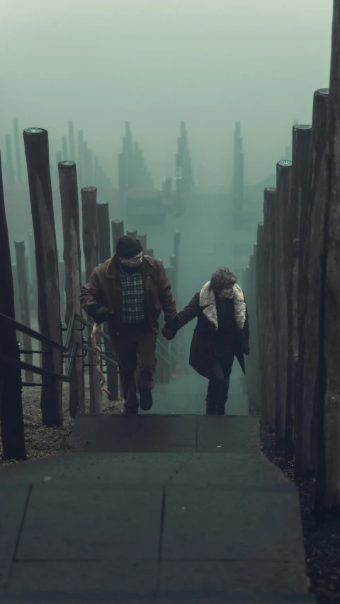 two people walking down a dark walkway on a foggy day