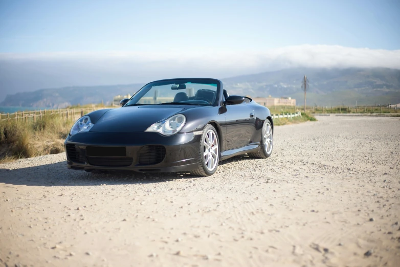 a black car sitting on top of a gravel road