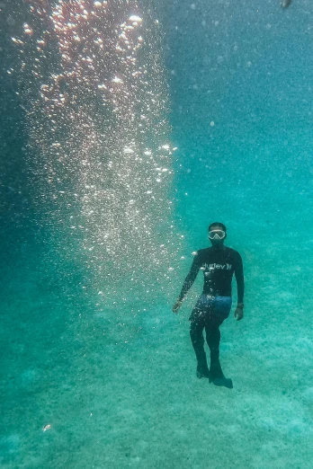 a man in a black wet suit is under water with his face submerged by an ocean wave