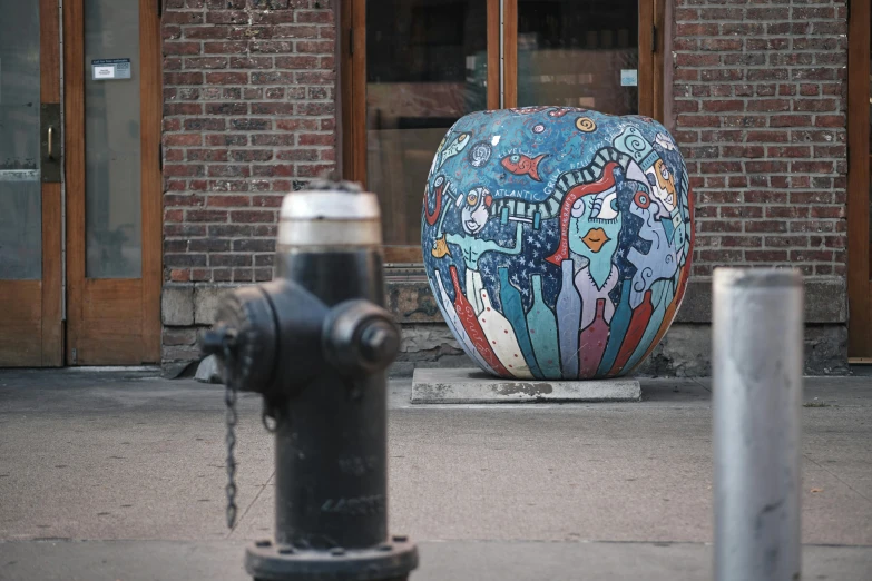 a large painted egg sitting next to a fire hydrant