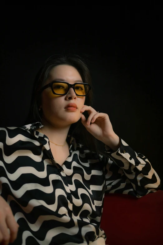 a woman in a shirt and glasses sitting down