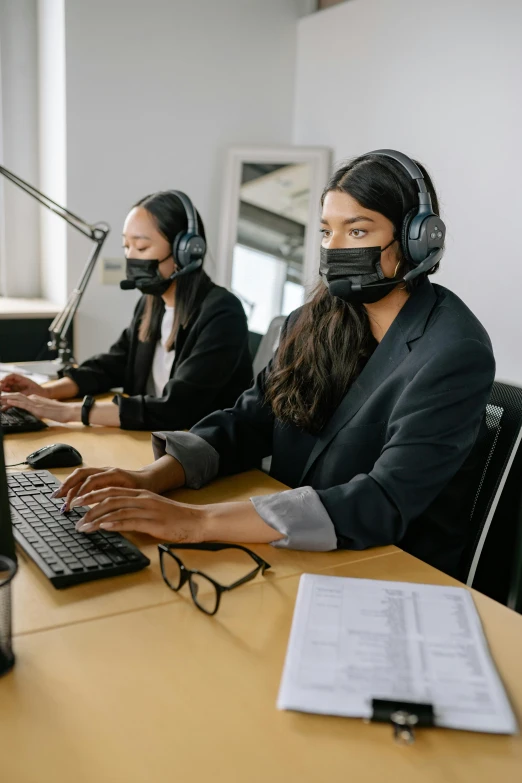 a couple of women sit at a table wearing headsets