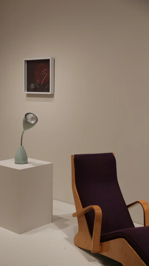 an artsic chair sitting next to a tall piece of artwork