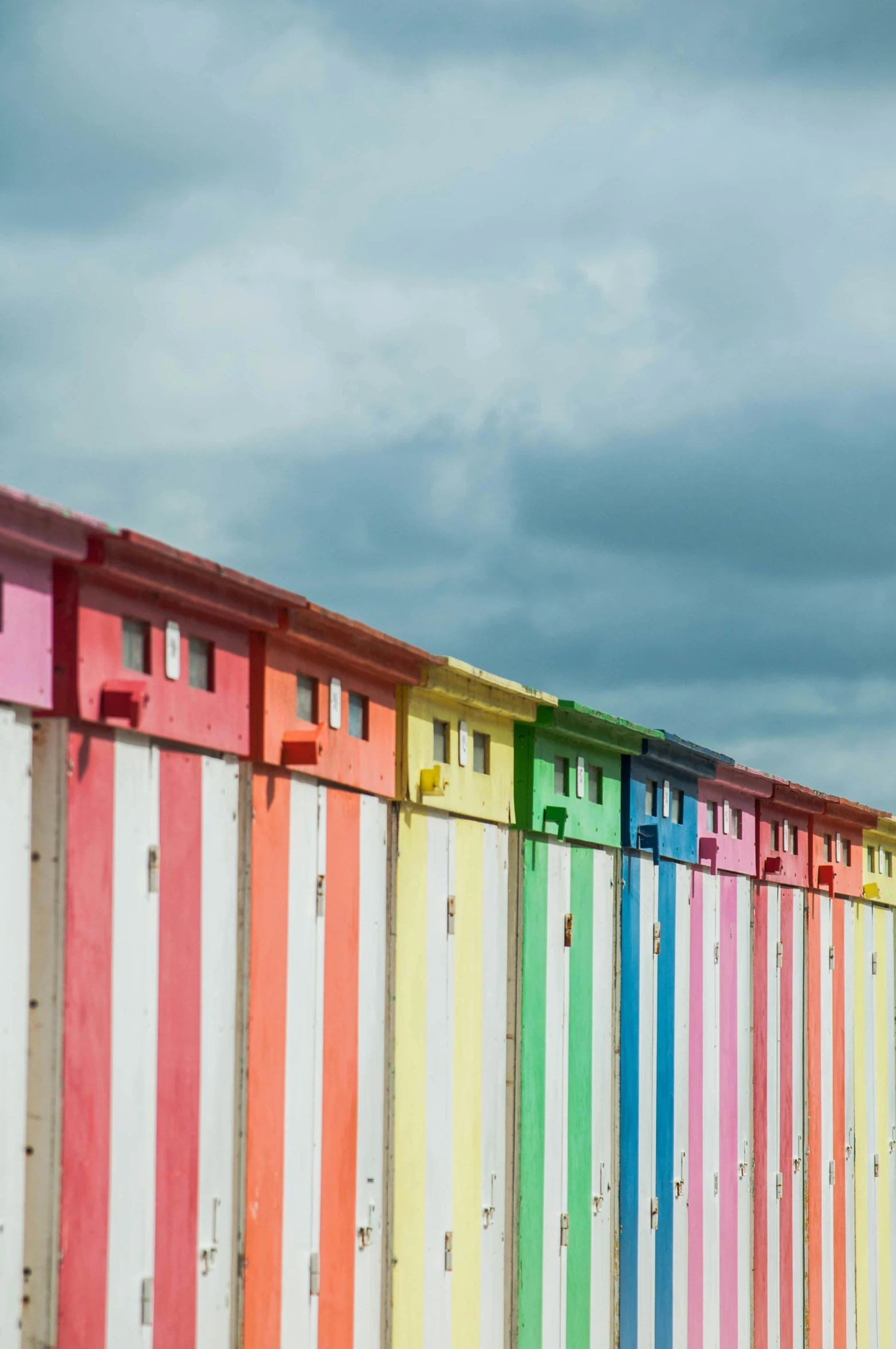 several multi - colored beach boxes are standing side by side on the sand