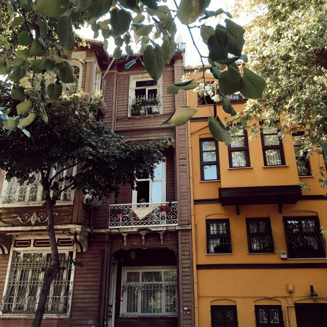 an orange two - story building with ornate balconies, an awning and a balcony