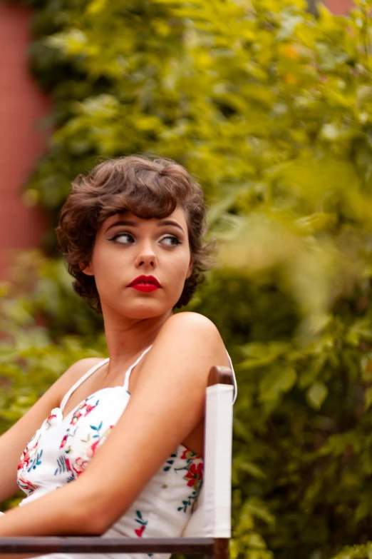 a woman in white sits on a chair with her eyes wide open