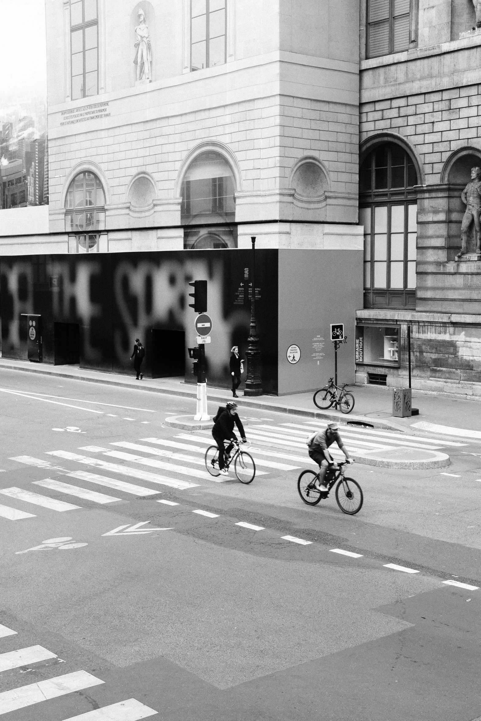 two people riding bicycles down the middle of a street