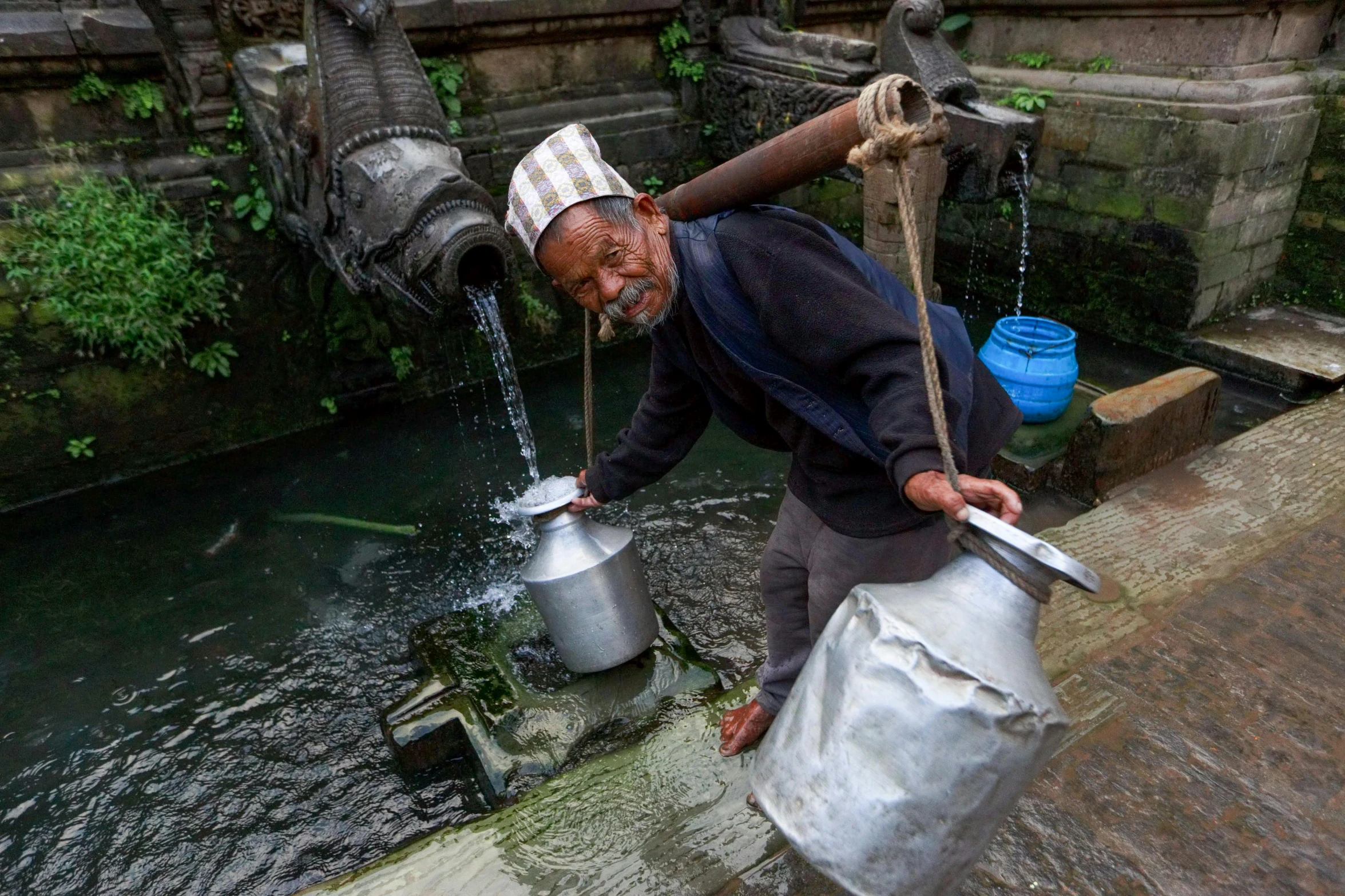 a man with a large metal jug pours water